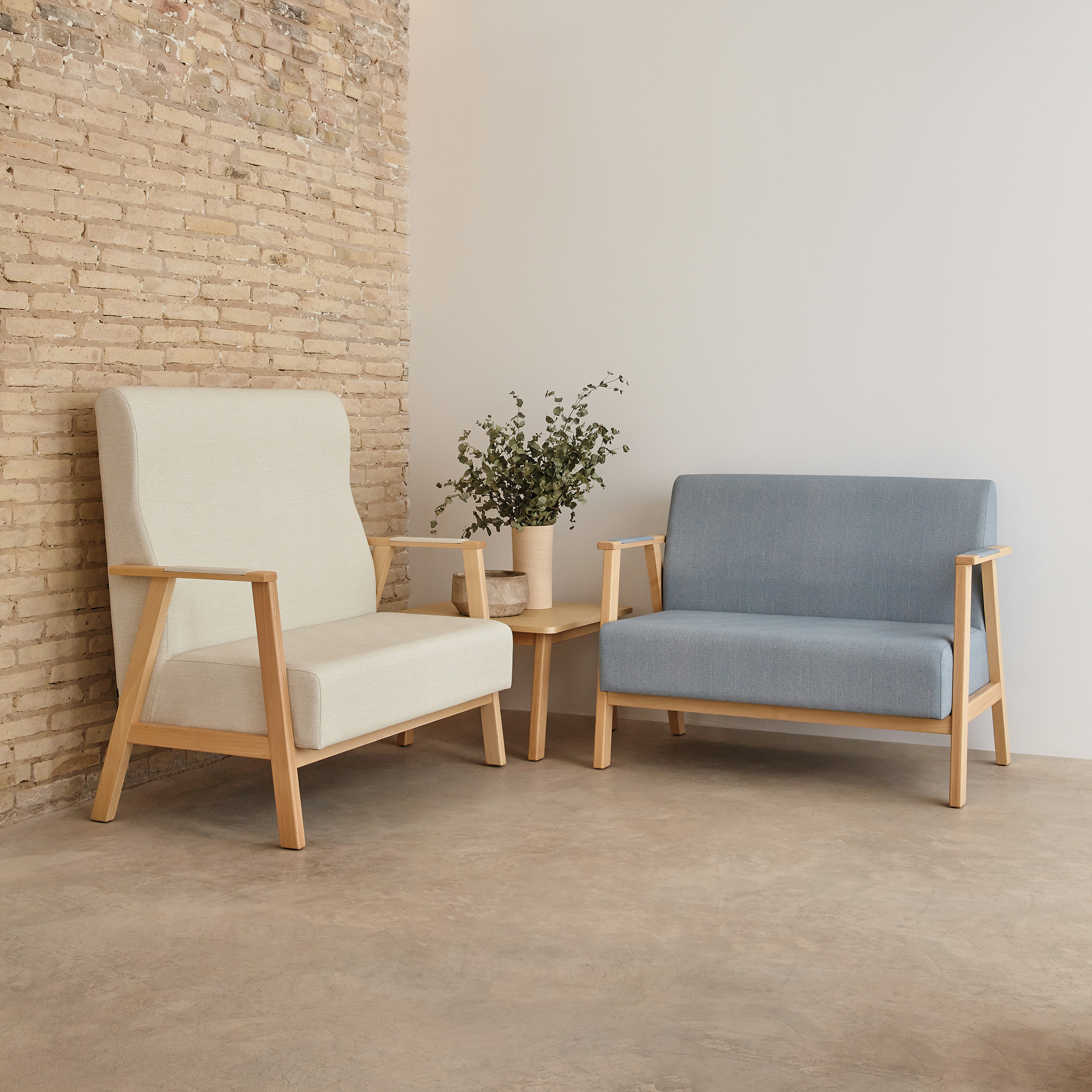 Hellblaues und beiges Sofa mit Holzarmlehnen und Holzfüßen in einer Raumecke, ergänzt durch einen hölzernen Beistelltisch mit Pflanze und Dekoschale in einem modernen Raum im Industrielook.